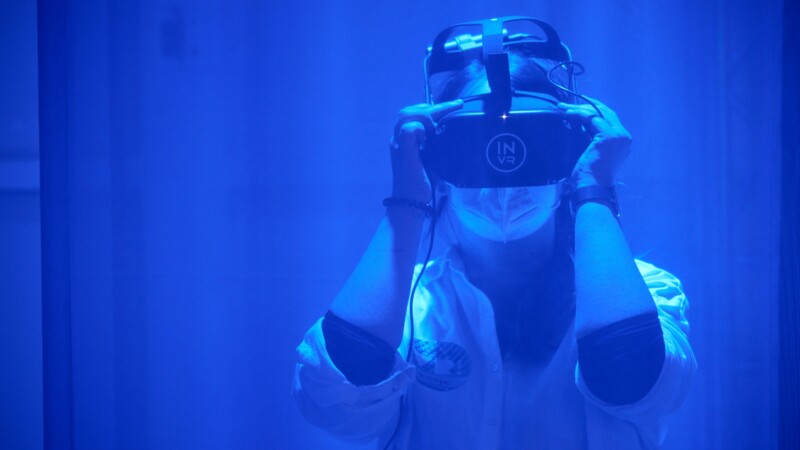 Eine Frau mit einer VR-Brille in blauem Licht getaucht