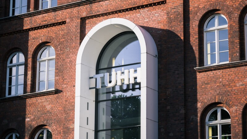 Brick building with large the letters “TUHH” on an arched window