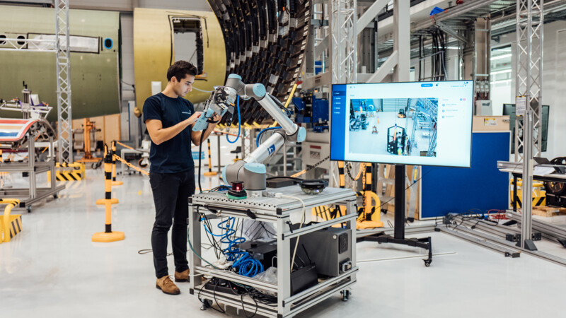 Mann steht in Industriehalle und bedient technischen Geräten