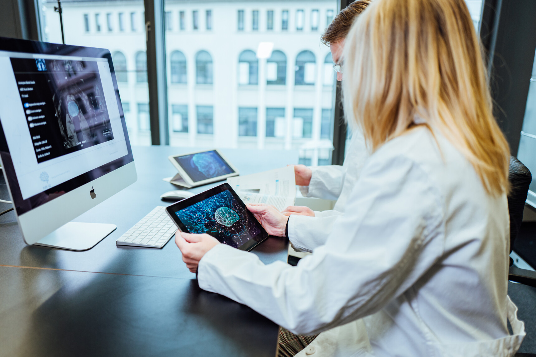 Künstliche Intelligenz: Zwei Ärzte schauen sich Daten auf einem Monitor und einem Tablet an