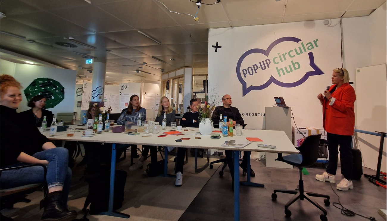 People sit attentively to a speaker in the Pop-Up Circular Hub
