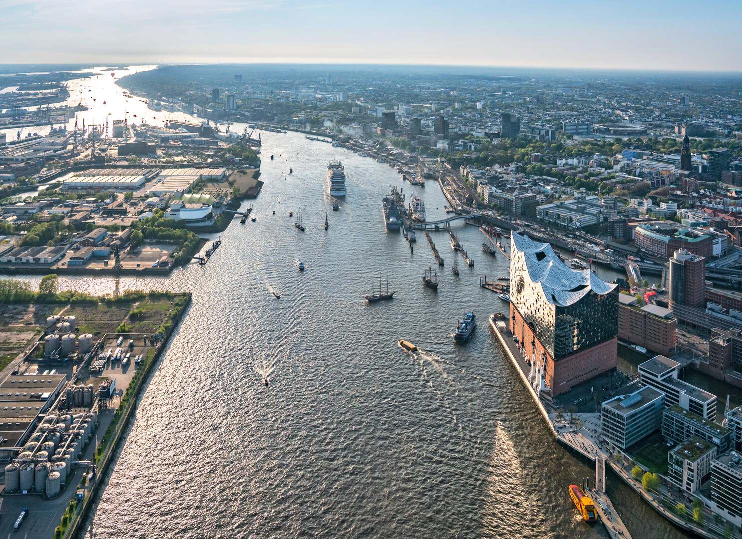 Luftaufnahme des Hamburger Hafens mit der Elbphilharmonie und verschiedenen Schiffen auf der Elbe.