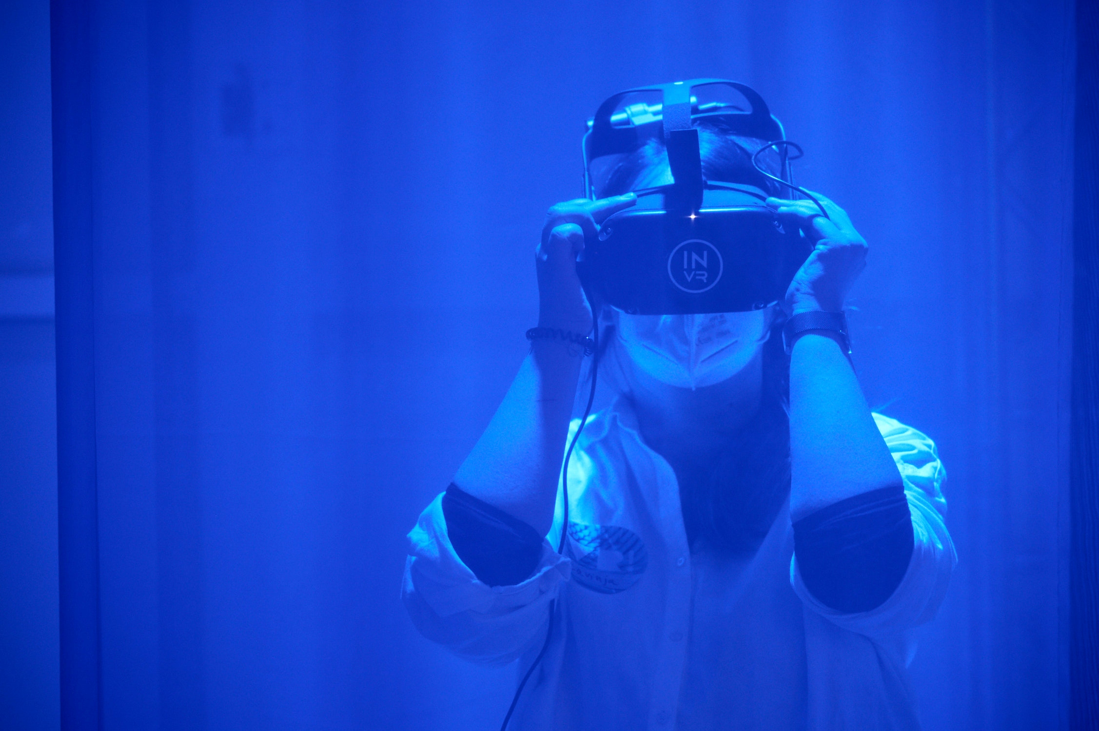 Eine Frau mit einer VR-Brille in blauem Licht getaucht