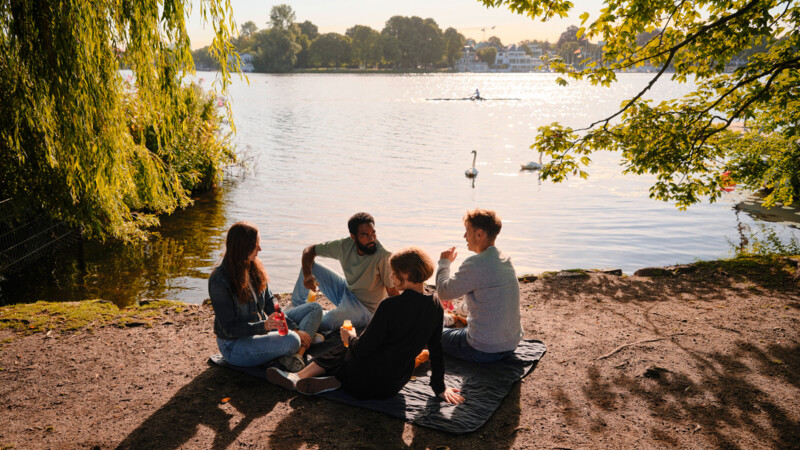 Junge Leute sitzen an der Alster