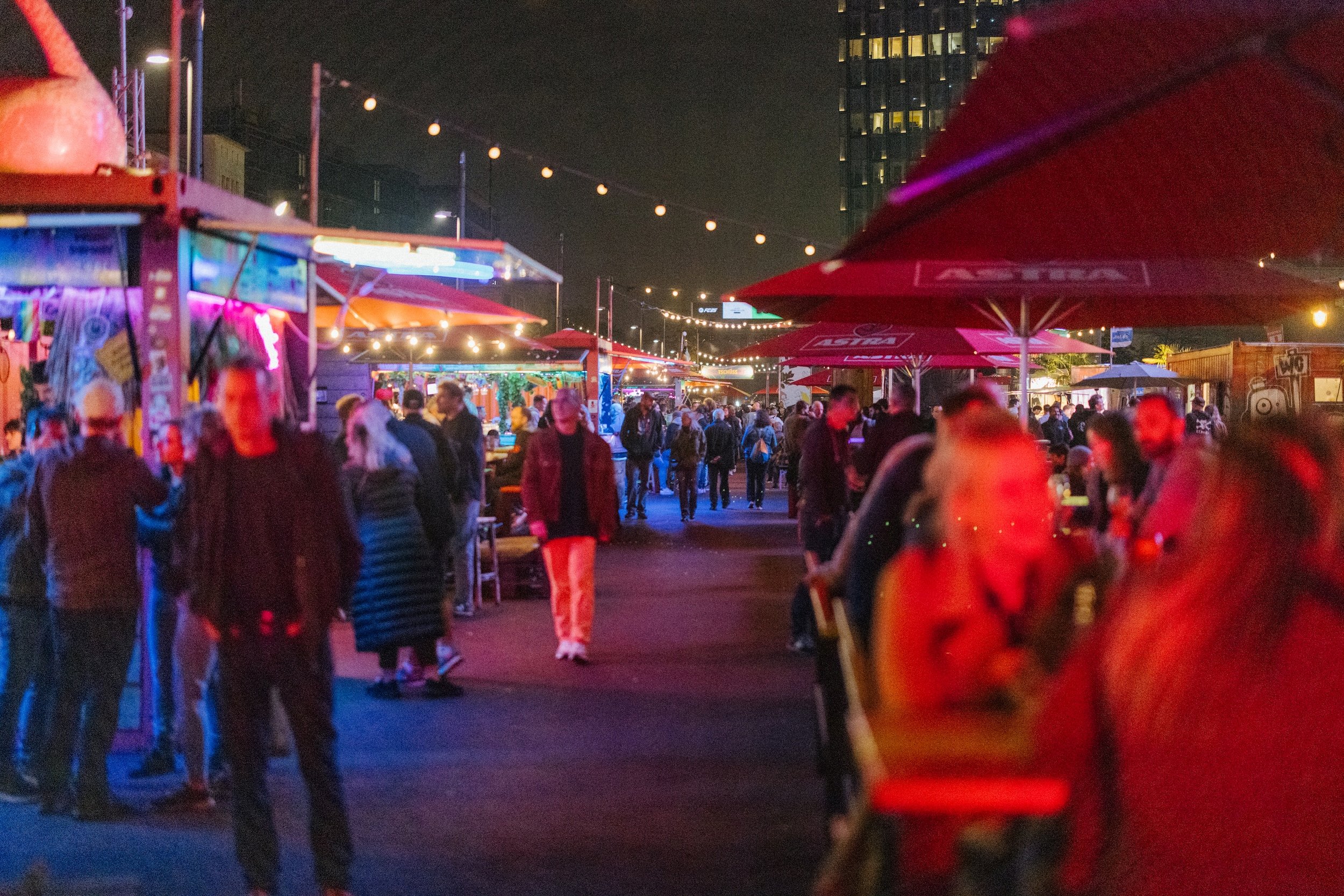 Spielbudenplatz at night with olourful lights and red parasols 