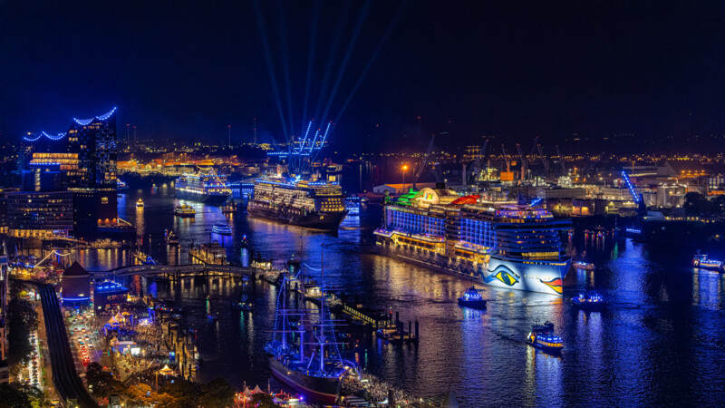 Port of Hamburg at night with blue-lit cruise ships and buildings