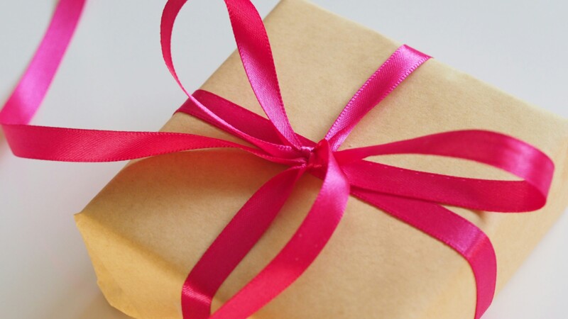 Geschenk in braunem Packpapier verpackt und mit pinker Schleife