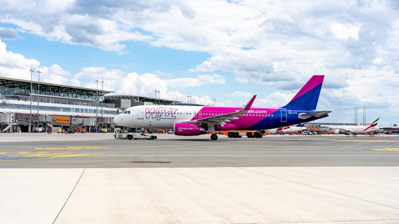 Ein Wizz Air Flugzeug steht auf dem Rollfeld vor dem Terminal eines Flughafens bei bewölktem Himmel.