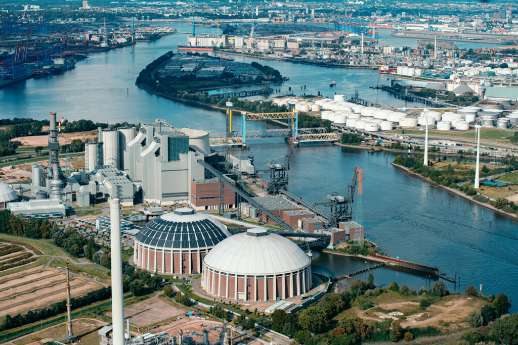 Luftaufnahme eines Industriehafens mit Silos, Fabrikgebäuden und Wasserwegen in einer urbanen Umgebung.