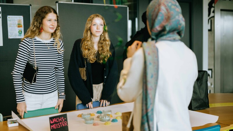 Schülerinnen informieren sich beim Young Makers Festival an einem Marktstand 