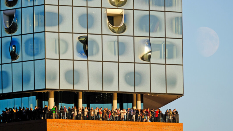 Menschenmenge auf Aussichtsplattform der Elbphilharmonie, oben moderne Glasfassade, unten Backsteinbau 