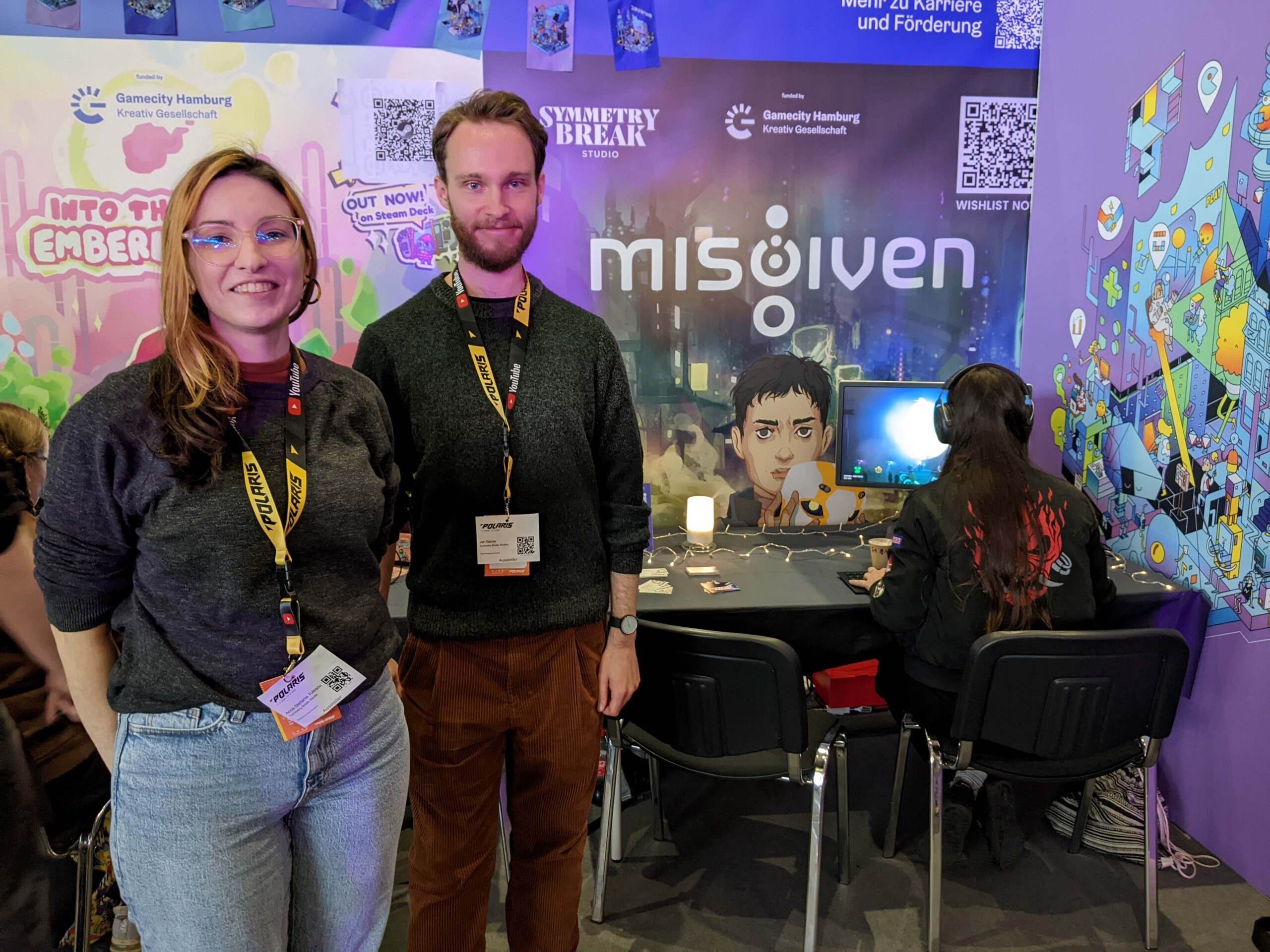 Anca Tutescu und Jan Barow, Co-Founder Symmetry Break Studio, vor ihrem Stand auf der Polaris. Im Hintergrund eine Spielerin des Adventure-Spiels Misgiven 