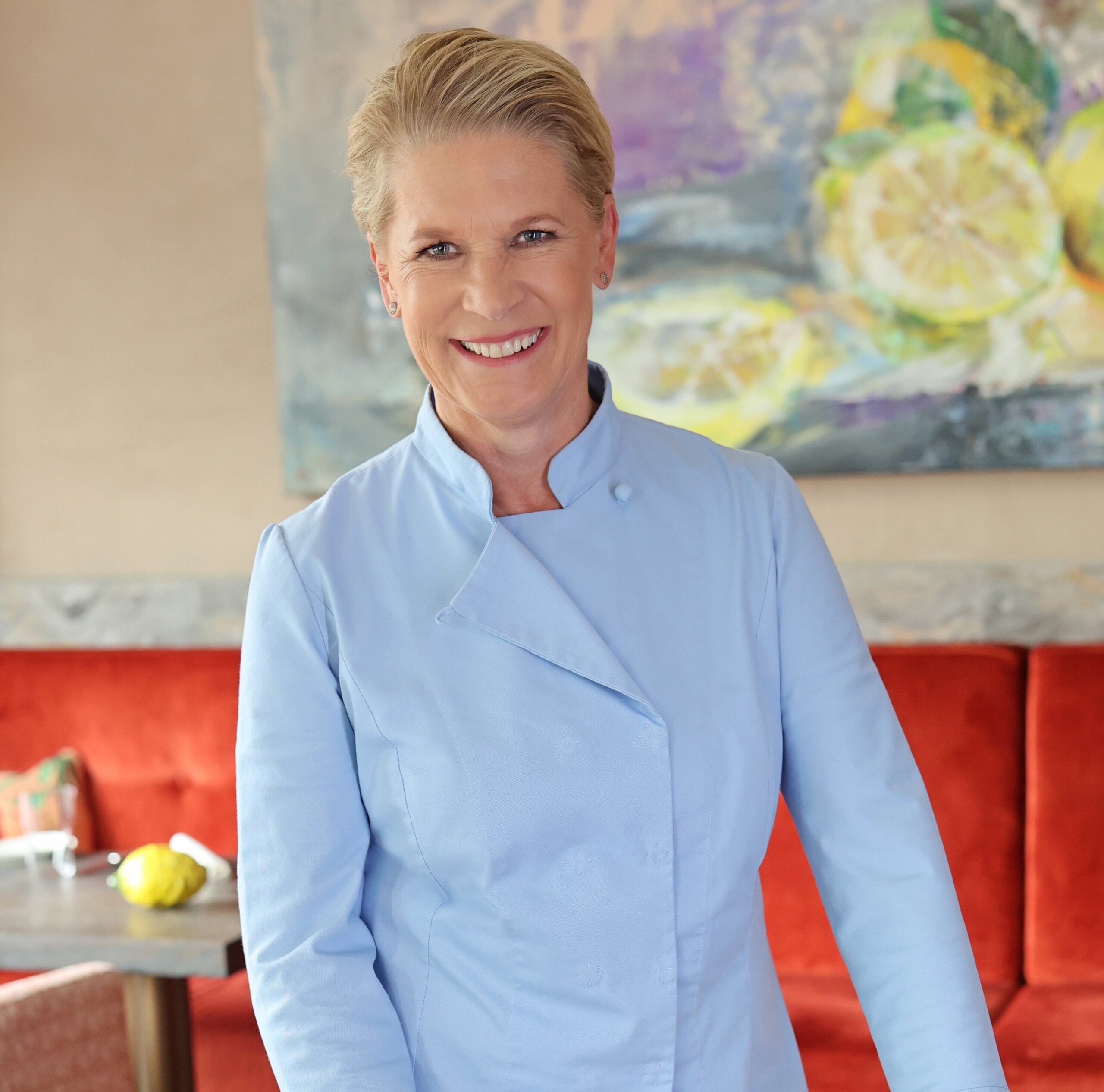 Female chef in blue garb checks  a table in a stylish restaurant