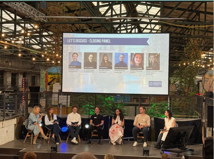 Sieben Personen unterhalten sich auf einem Panel