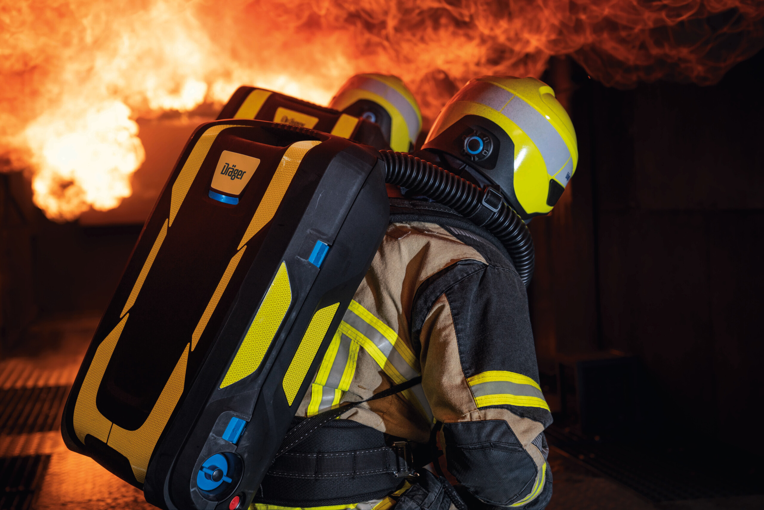Two firefighters with oxygen tanks face huge flames