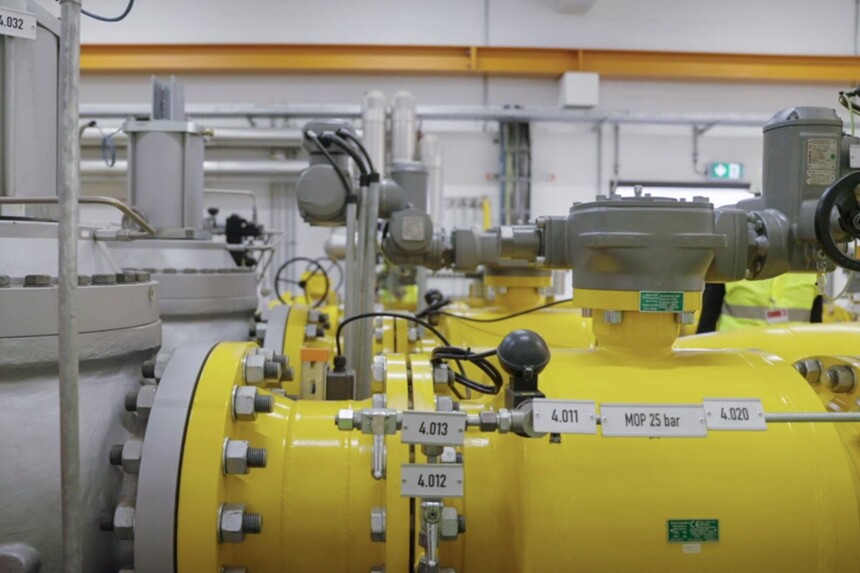 Industrielle gelbe Rohrleitungen und Ventile in einer technischen Anlage mit Beschilderung und Steuergeräten.