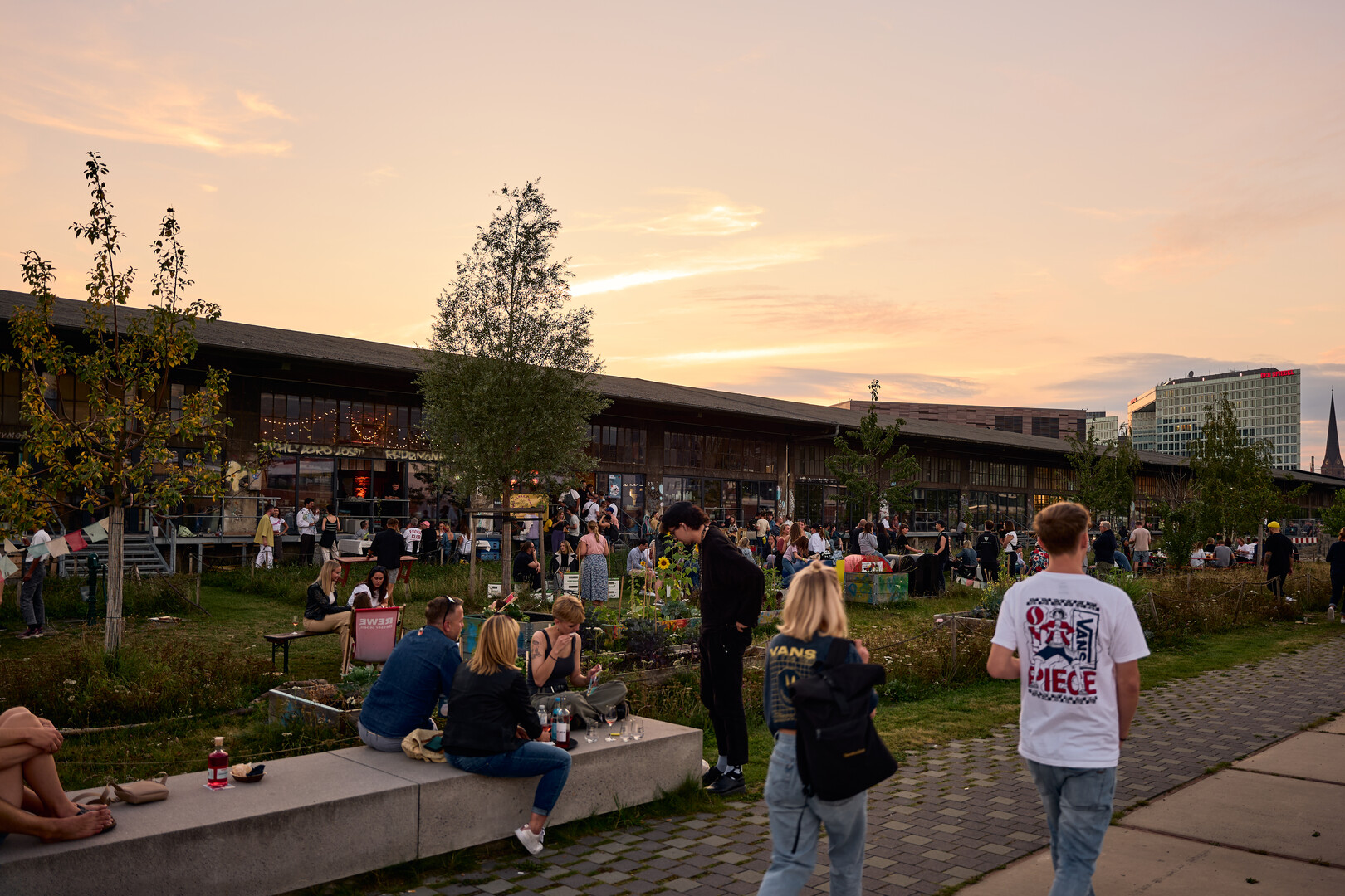 Symbolic image of creative interim use: the Oberhafen quarter. The picture shows many people sitting and standing in front of the Oberhafen's brick buildings, taken at a food festival in 2023