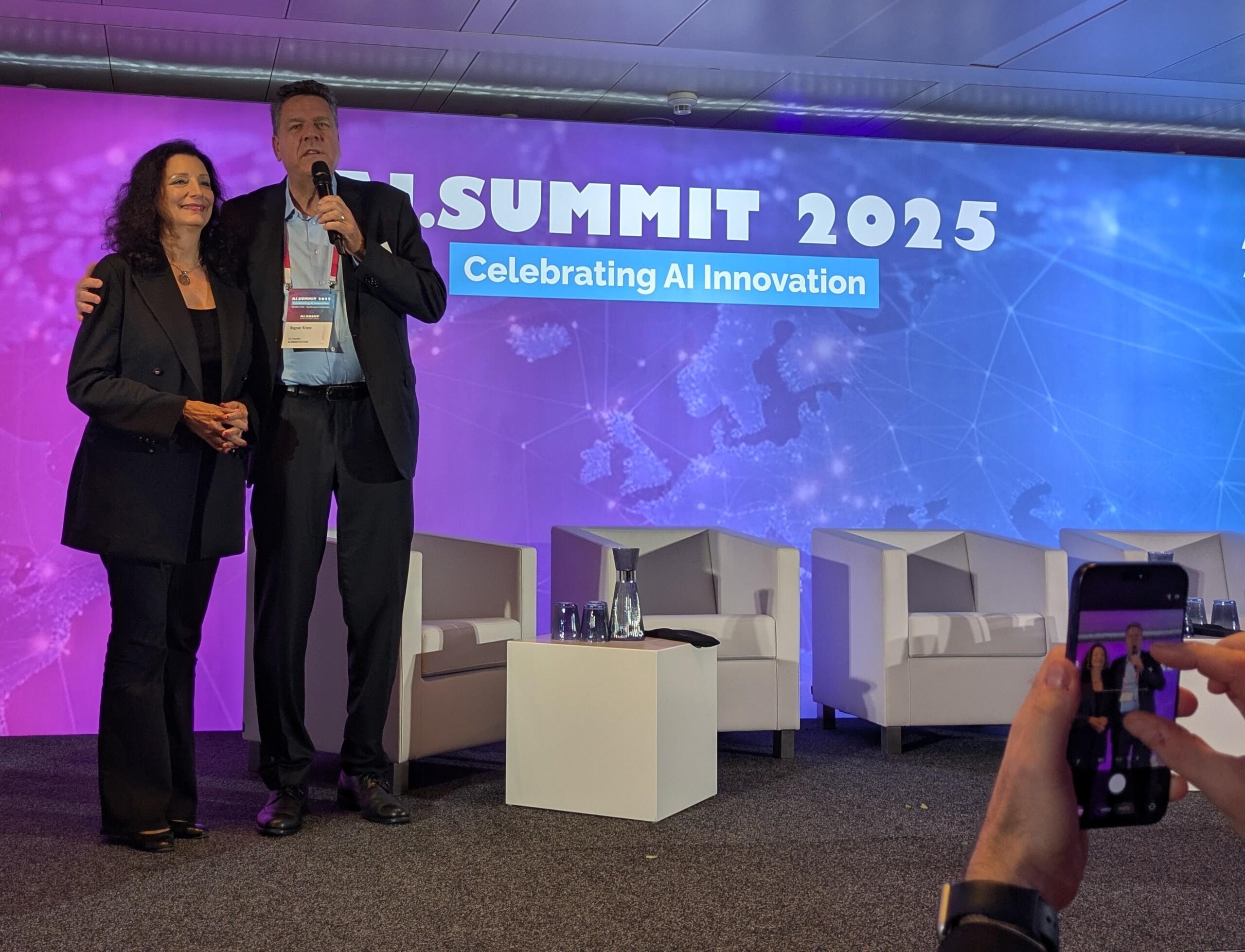 Petra Vorsteher and Ragnar Kruse on stage against a backdrop reading "AI Summit 2025"