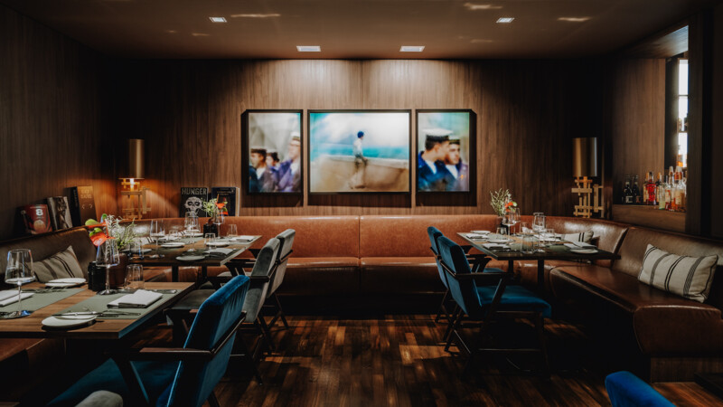 Elegantes Restaurant mit Lederbänken, blauen Stühlen, gedeckten Tischen und moderner Wandkunst.