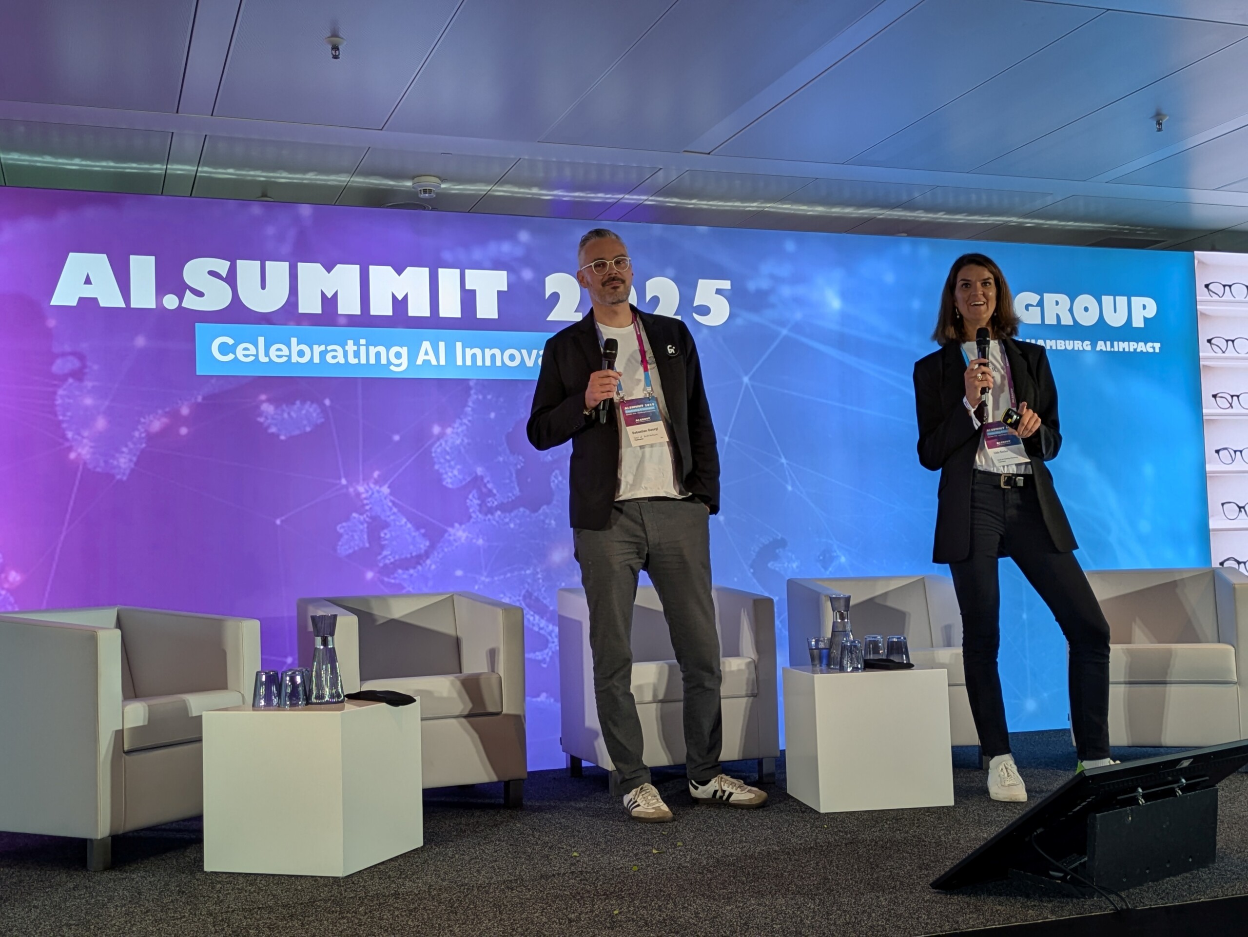 Edda Becker and Sebastian Georgi on stage during the AI.SUMMIT 2025