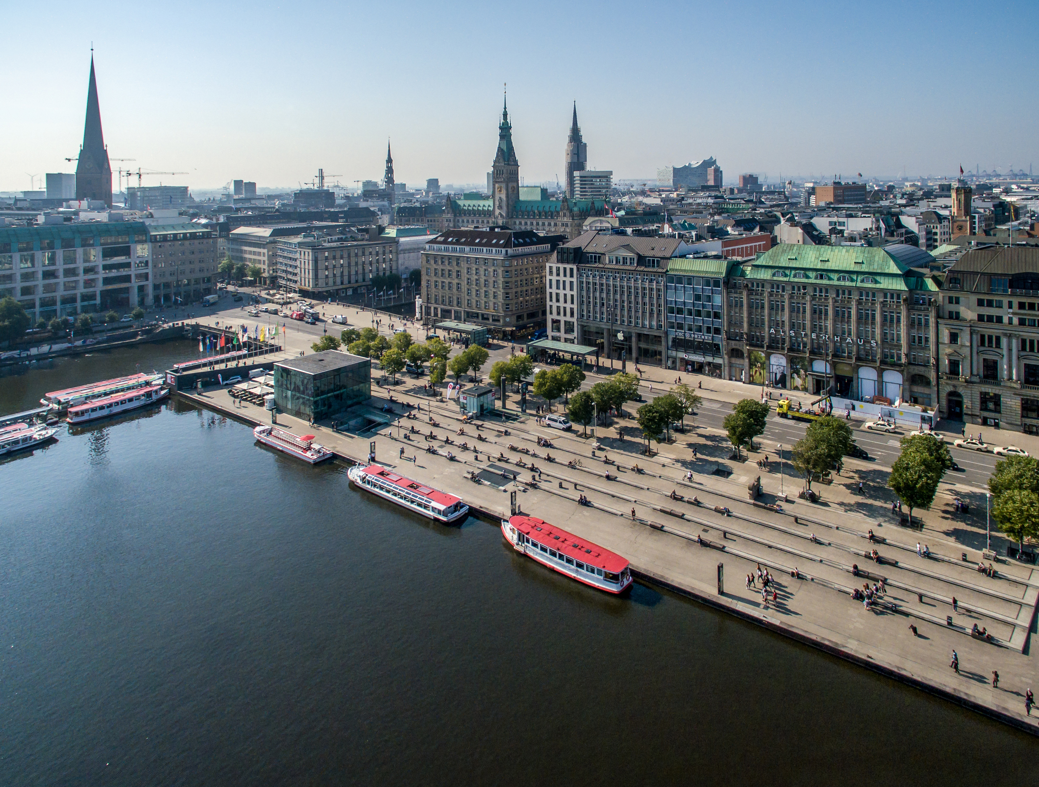 Aerial view of Hamburg's Inner Alster with piers, boats and the city center in the background under a clear sky.
