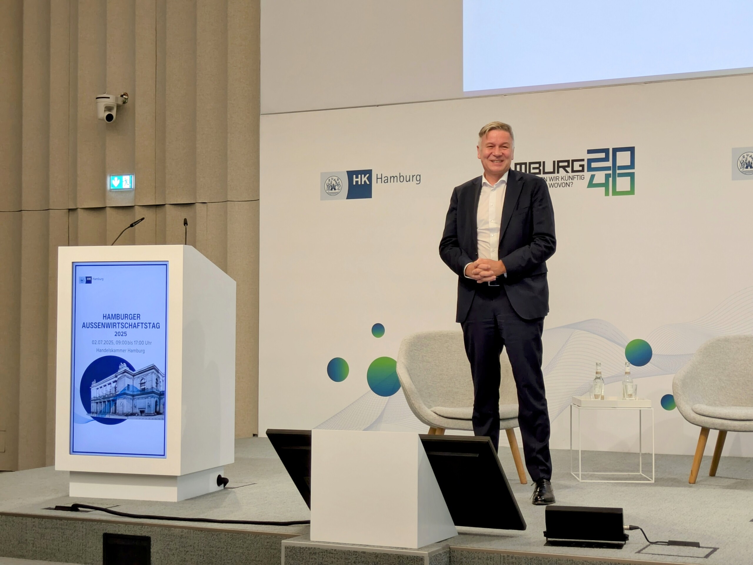 USA-Experte Josef Braml steht lächelnd auf dem Podium in der Handelskammer Hamburg