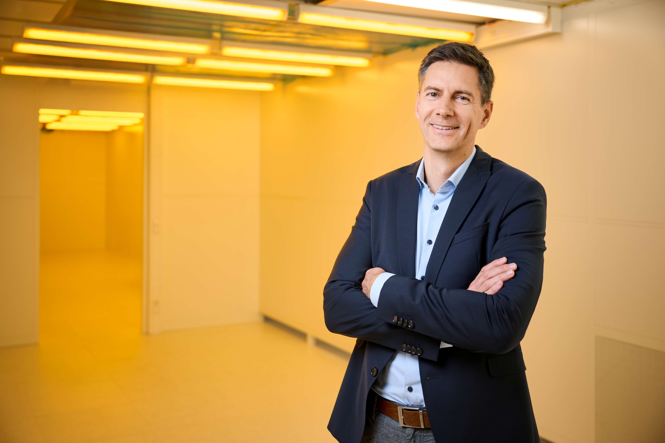Dr Robert Axmann stands in a yellow-lit corridor