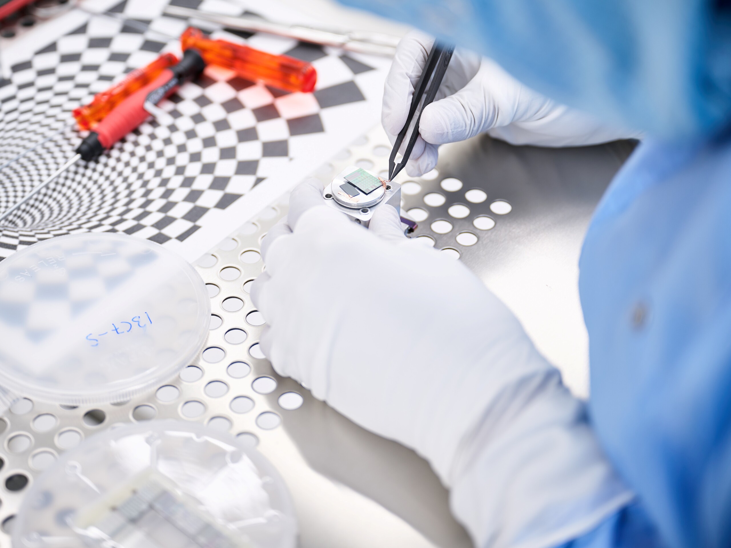 Laboratory technician puts microchip on a metal plate in a clean room