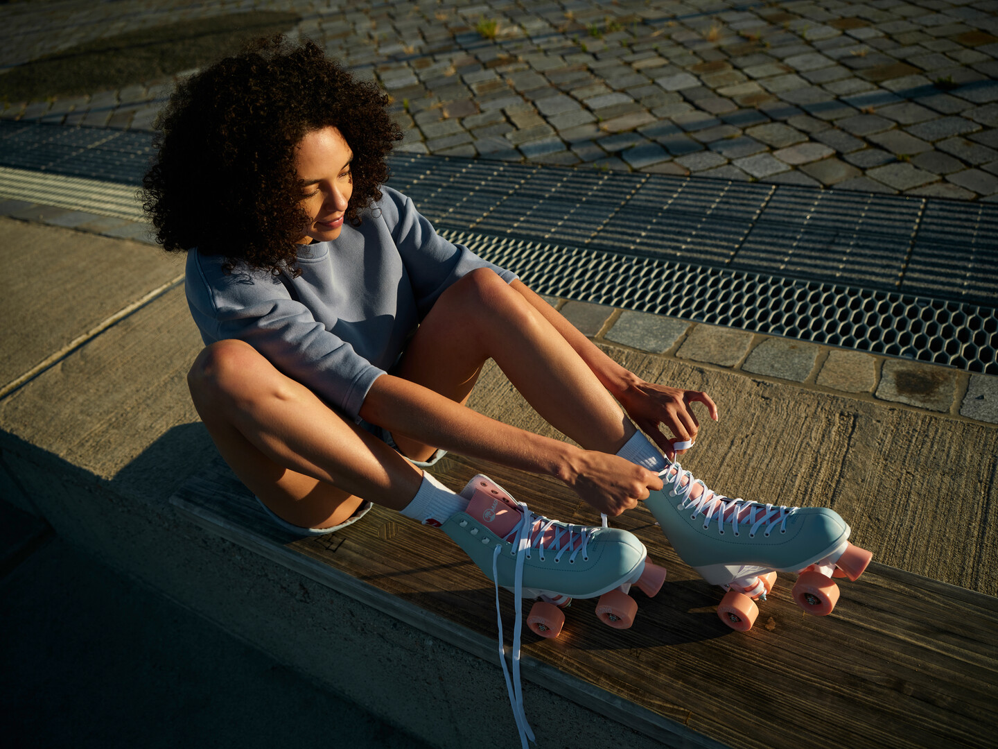 Symbolic photo Young talent and movement towards the future: Young woman sitting on a bench outside and lacing up her roller skates.
