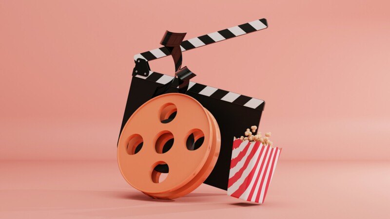 Filmklappe, Filmrolle und Popcorntüte vor rosa Hintergrund.