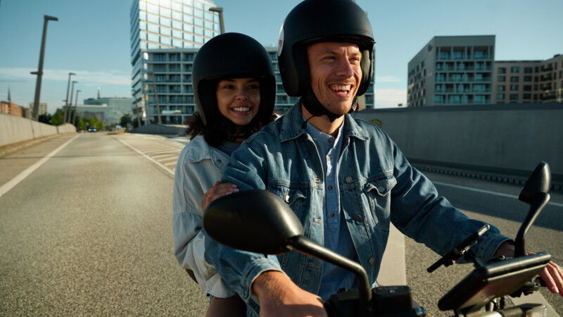 Couple riding a scooter and wearing helmets