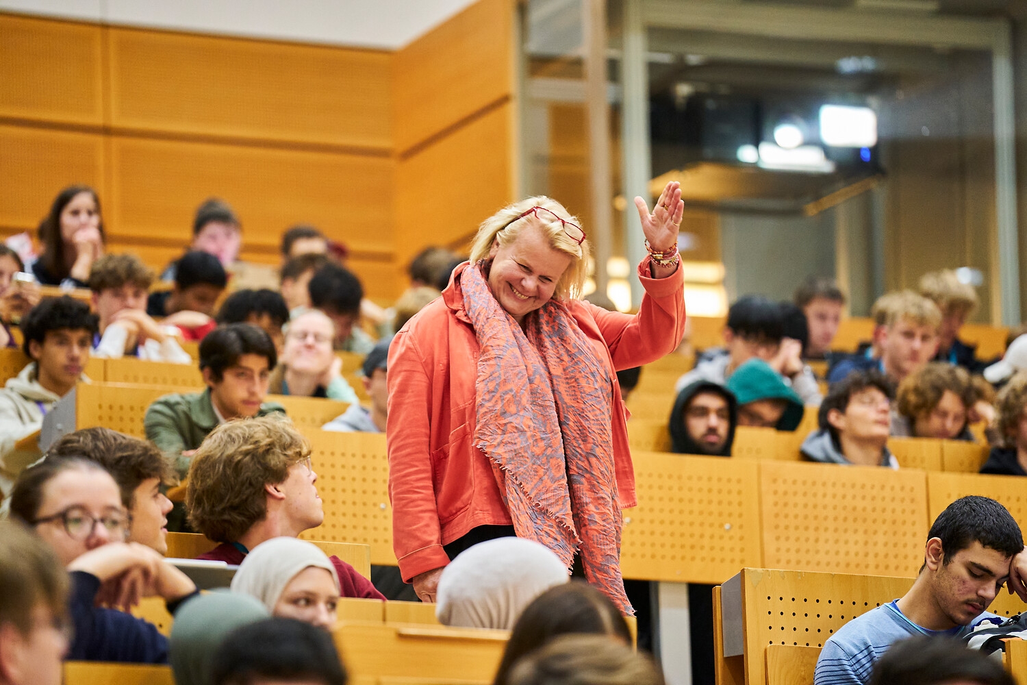 A smiling professor greets students in a lecture hall