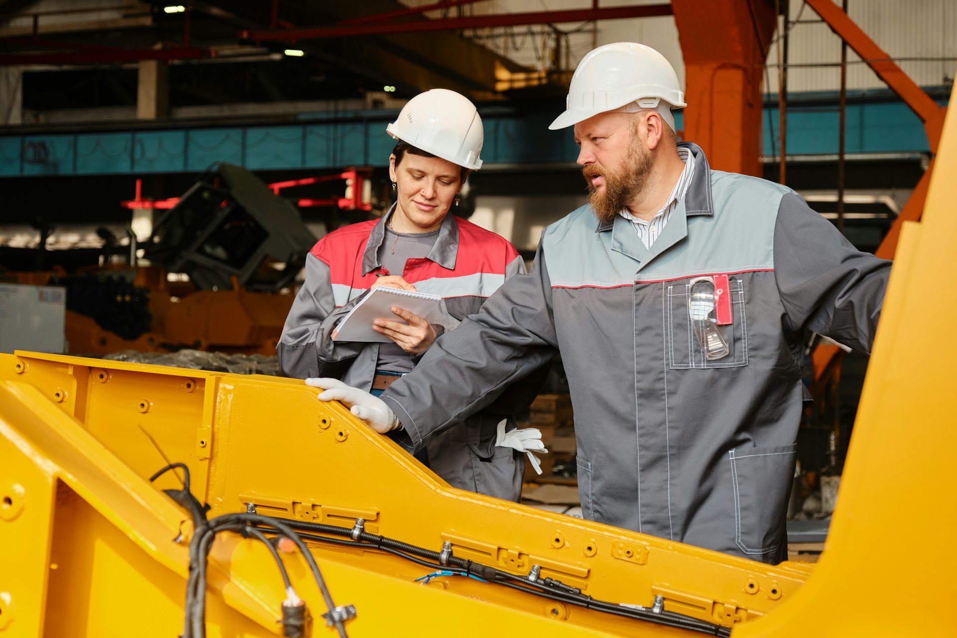 Ein Industriearbeiter und eine Industriearbeiterin in einer Fertigungshalle