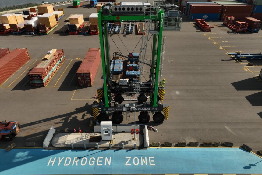Großer grüner Hafenkran in einer als „Hydrogen Zone“ markierten Ladezone mit Containern im Hintergrund.