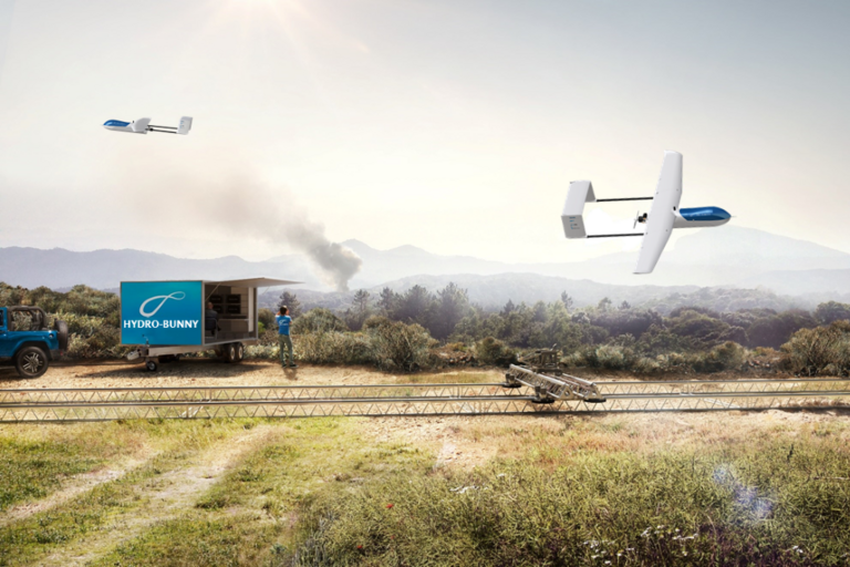 Zwei Drohnen fliegen über ein Feld mit landwirtschaftlicher Ausrüstung und einem Hydrobunny-Mobil.