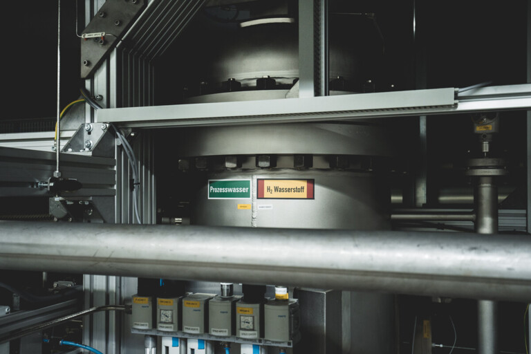 Industrielle Anlage mit beschrifteten Rohren für Prozesswasser und Wasserstoff.