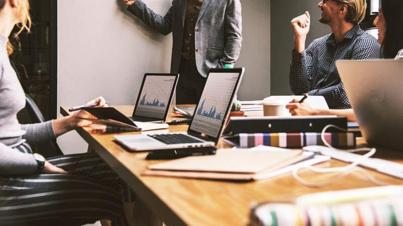 Arbeitssituation am Schreibtisch mit Menschen an aufgeklappten Laptops