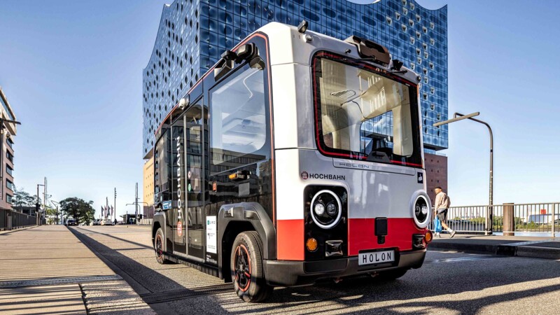 Kleiner autonomer Elektrobus Holon vor der Elbphilharmonie in Hamburg bei sonnigem Wetter.